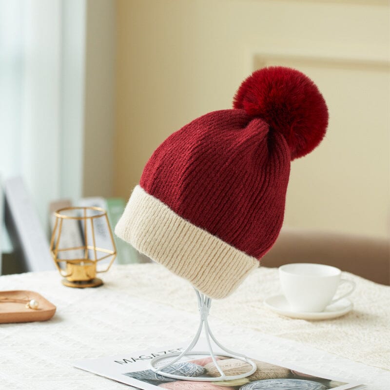 bonnet polaire rouge avec un pompon surmonté de laine crème pour garder la tête au chaud en hiver