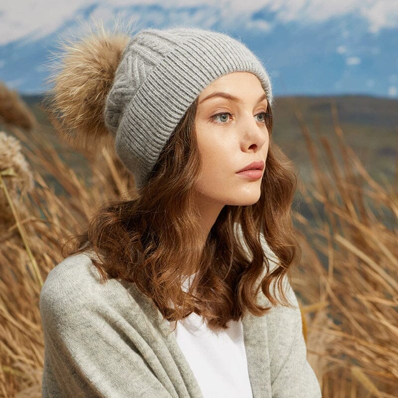 femme portant un bonnet pompon claire en hiver avec un pompon amovible dans un paysage de montagne