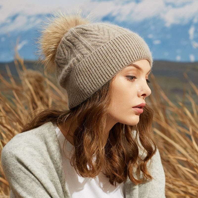 bonnet pompon amovible clair, modèle porté par une femme en extérieur avec un paysage de montagnes en arrière-plan