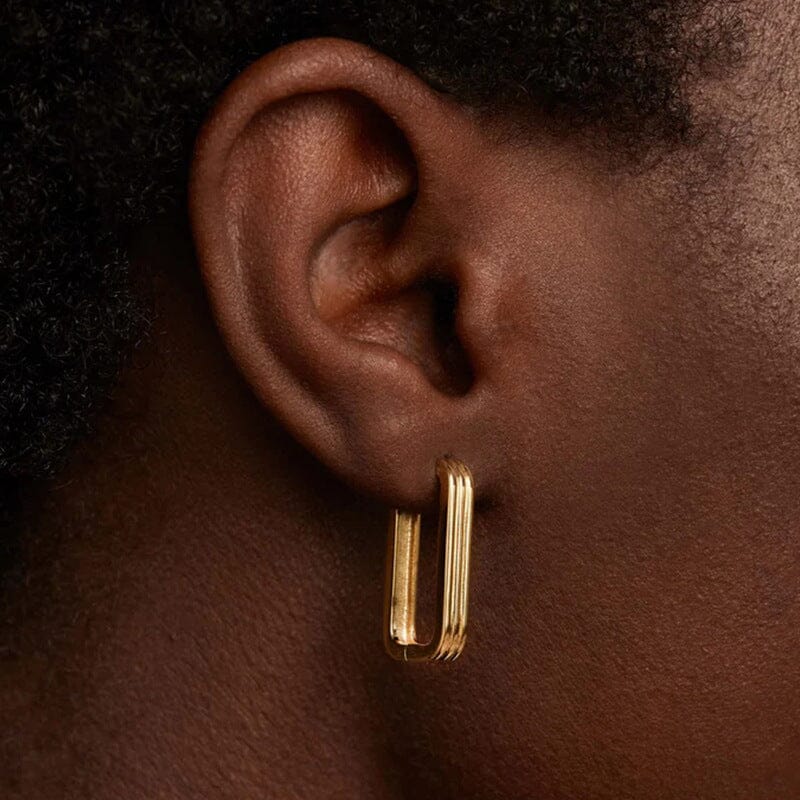 créole rectangulaire dorée aida portée sur une oreille, bijou minimaliste et élégant pour un style moderne et raffiné