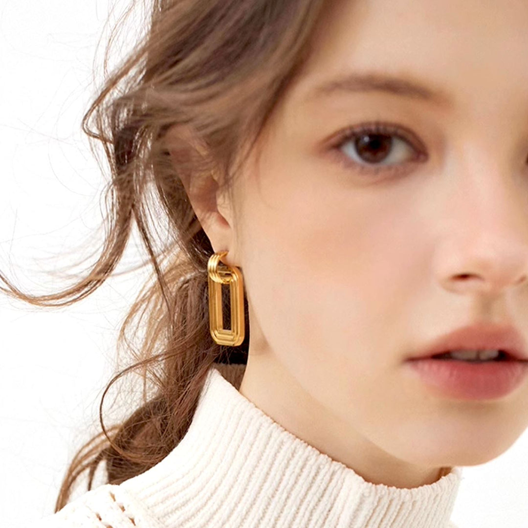 boucles d'oreilles rectangulaires en or portées par une femme, accessoire élégant et moderne pour toutes occasions