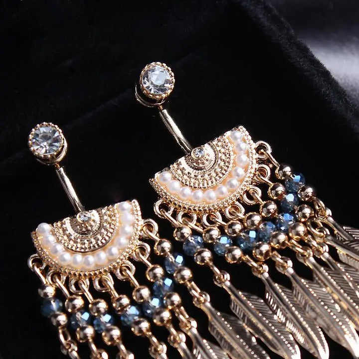 boucles d'oreilles pendantes avec des plumes en métal doré, accentuées de perles et pierres bleues, style amérindien