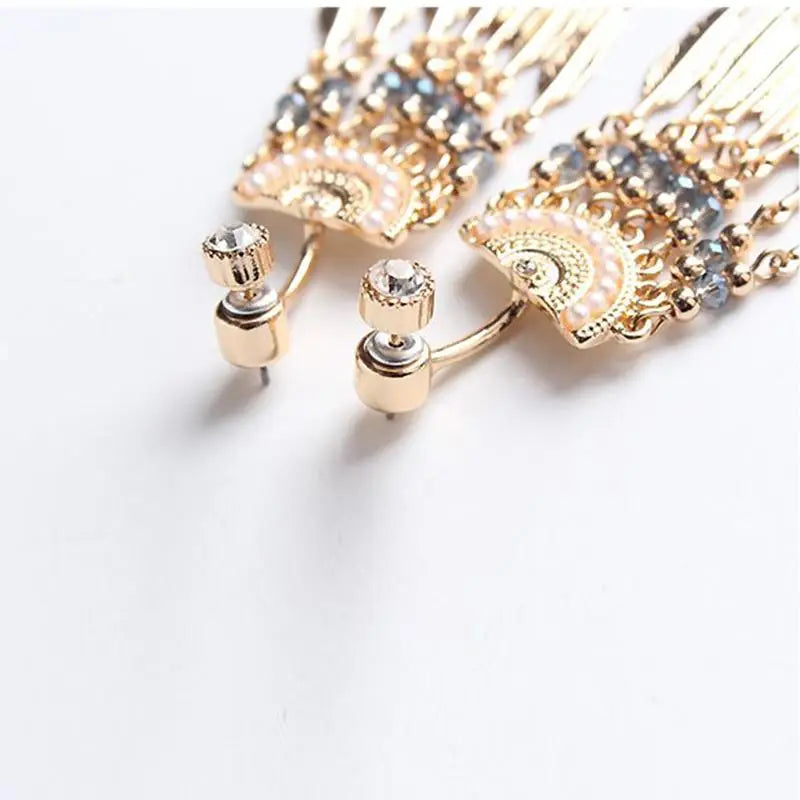 boucles d'oreilles plumes amérindiennes en métal doré et cristaux brillants, style ethnique chic, gros plan détaillé