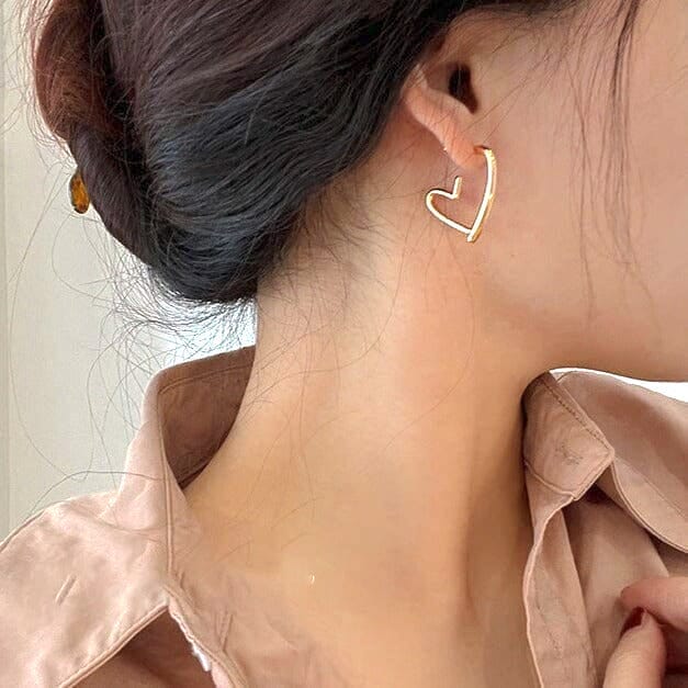 Boucles d'oreilles en forme de cœur dorées portée par une femme avec les cheveux relevés, détail chic et élégant.