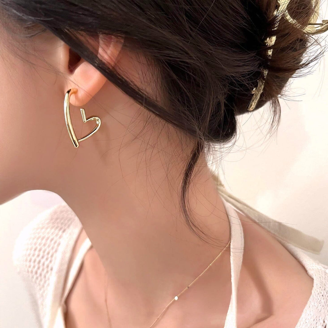 boucles d'oreilles en forme de cœur en or portées par une femme de profil', un bel accessoire de bijouterie élégant et raffiné