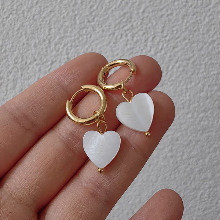 boucles d'oreilles en or avec pendentif en forme de cœur nacré, modèle irma, tenues sur fond blanc structuré