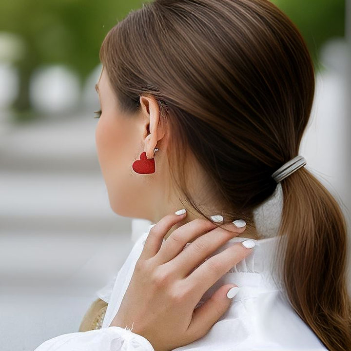 Boucles d'oreilles élégantes en forme de cœur rouge portées, parfaites pour une touche romantique et sophistiquée.