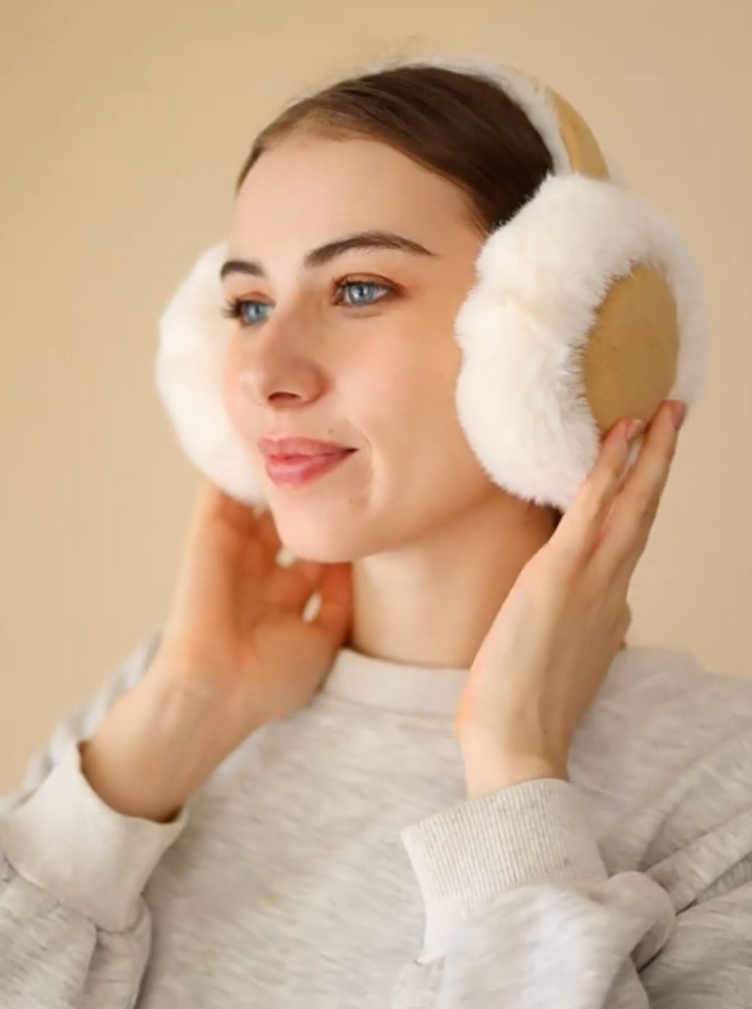 cache oreille elise femme en laine polaire blanche pour l'hiver, porté par un modèle souriant avec un pull gris clair