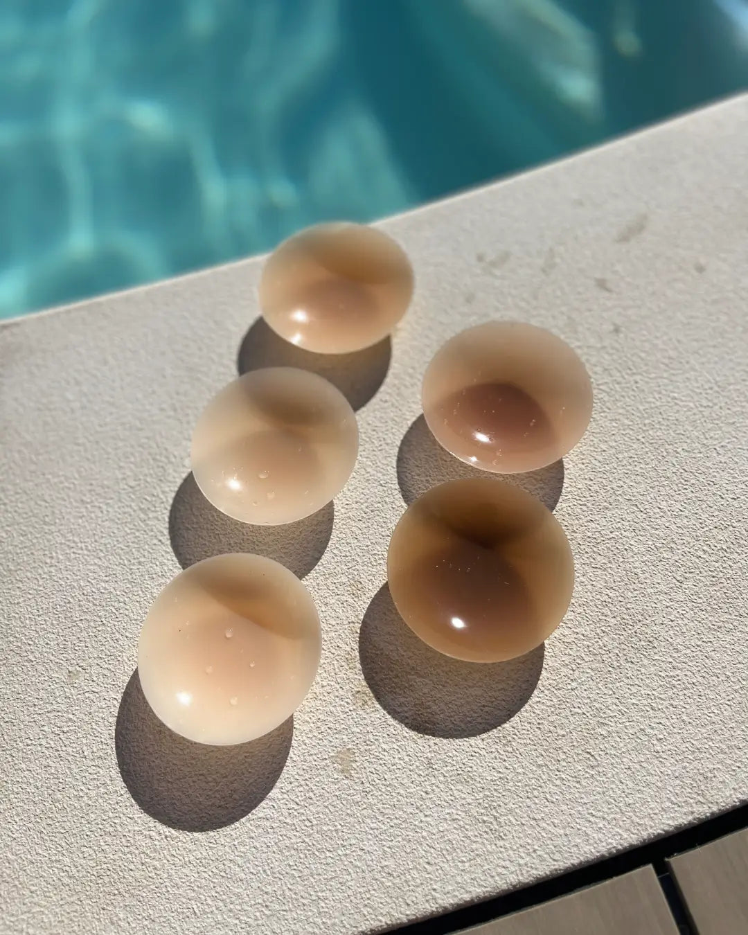 Lot de cache-tétons invisibles en silicone posés près d'une piscine, sans adhésif, idéal pour confort et discrétion.