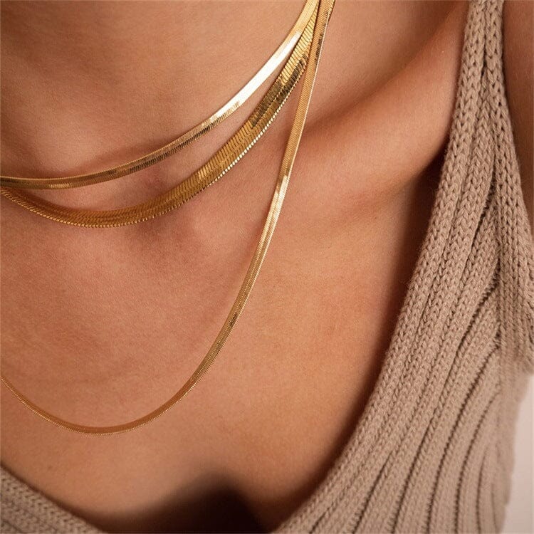chaîne dorée emma au design maille miroir pour femme, bijou élégant et tendance, porté sur un décolleté en tricot beige