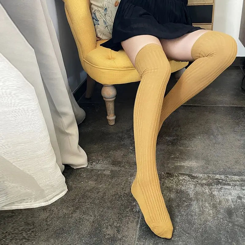 chaussettes hautes mi cuisses femme en laine et coton couleur jaune porté assise sur une chaise dans un environnement intérieur