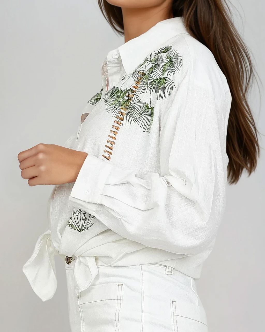 Chemise blanche oversize avec motif floral sur l'épaule et manches longues, idéale pour un style décontracté et élégant.