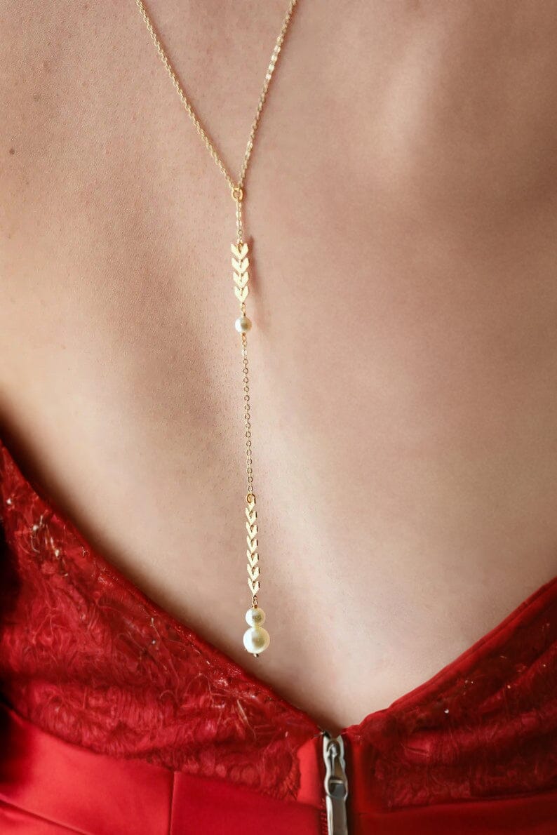 collier de dos bohème melina en or avec perles, idéal pour les mariées, porté avec une robe rouge élégante