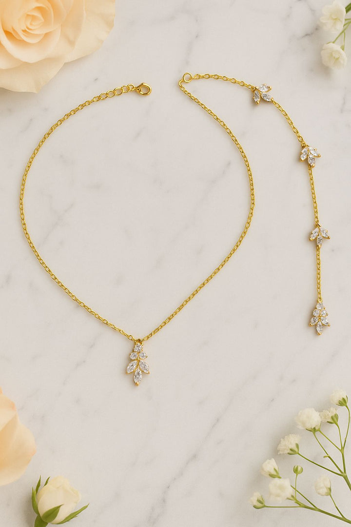 Collier de dos élégant pour mariée, modèle Augustine, avec ornements brillants sur fond de marbre et fleurs délicates.