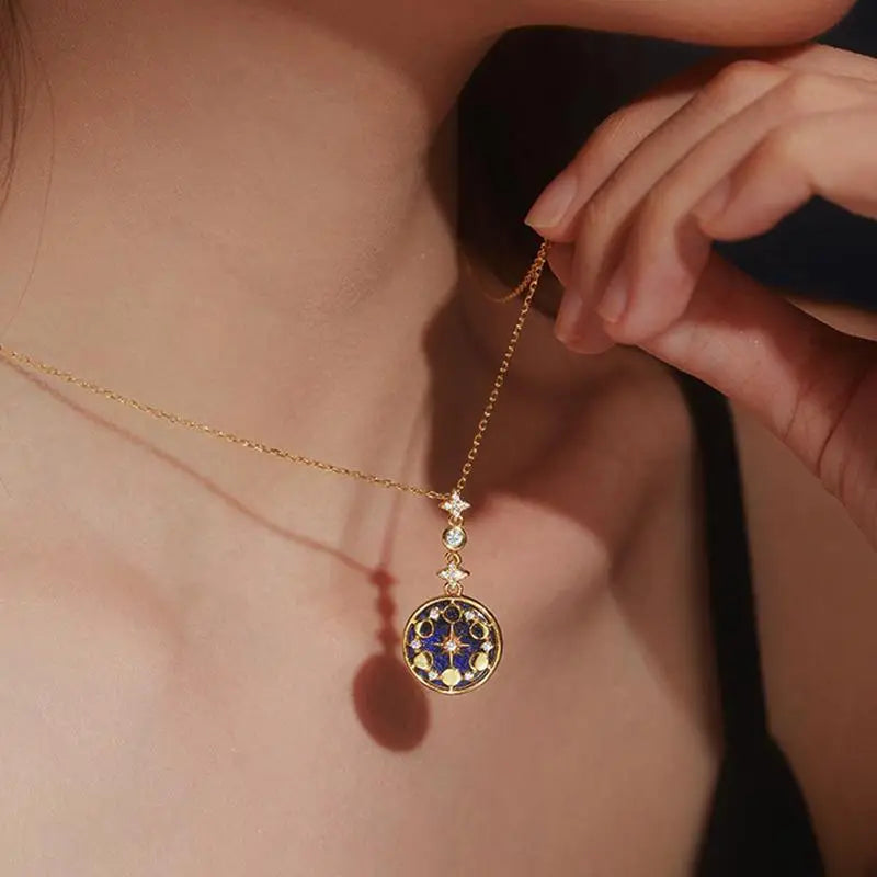 collier médaillon or avec ciel étoilé et cycle lunaire porté par une femme, parfait pour compléter une tenue élégante