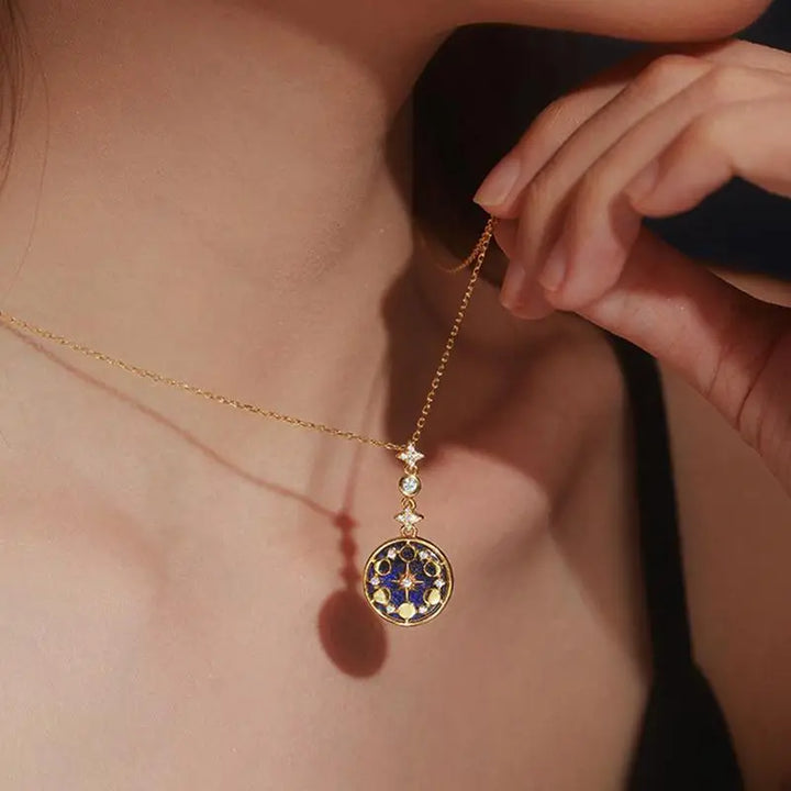 collier médaillon or avec ciel étoilé et cycle lunaire porté par une femme, parfait pour compléter une tenue élégante