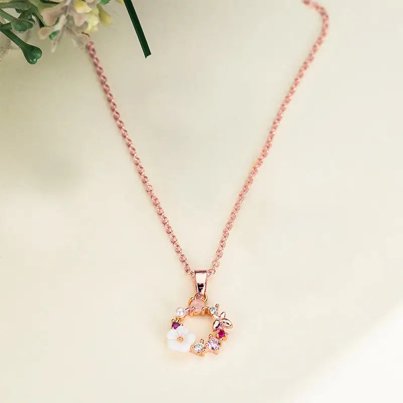 collier pendentif délicat en or rose en forme de couronne de fleurs avec détails roses et blancs, idéal pour un cadeau