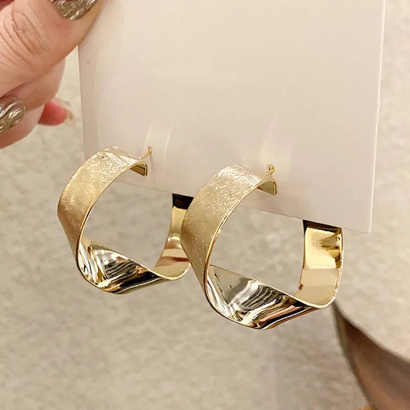 créoles dorées en forme de boucle avec une finition brillante et texturée idéales pour un look élégant et moderne