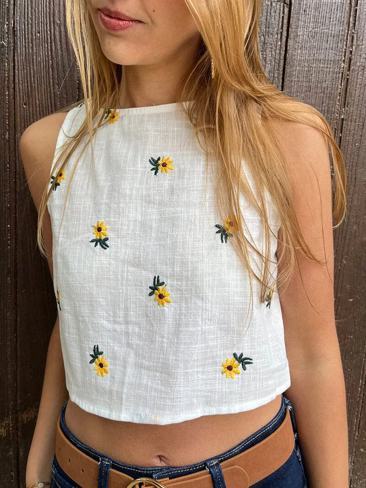 top blanc fleuri sans manches misha porté avec jean, parfait pour un look estival et élégant avec des motifs floraux jaunes
