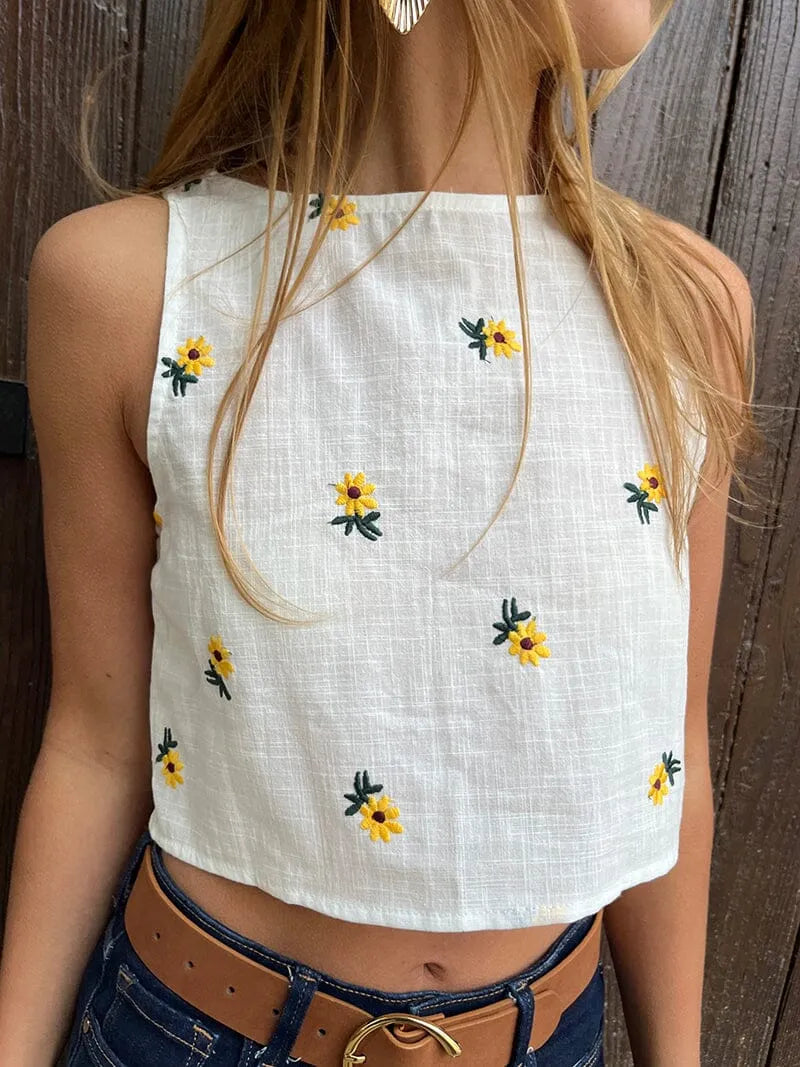 top blanc fleuri sans manches misha porté avec jean, parfait pour un look estival et élégant avec des motifs floraux jaunes