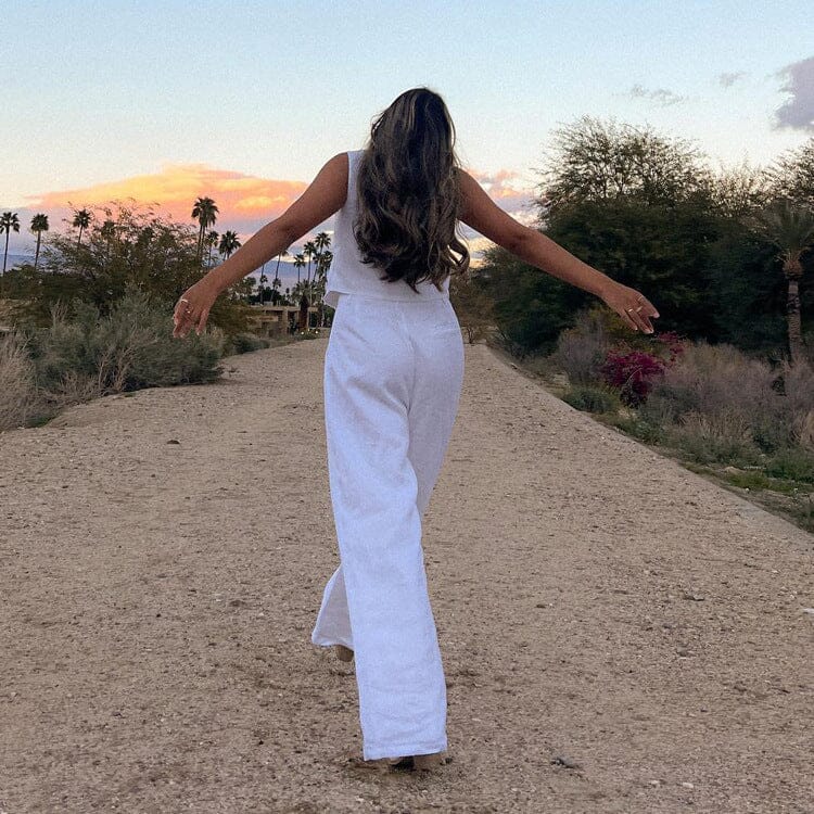 femme portant l'ensemble pantalon leona blanc marchant sur un chemin en plein air avec un coucher de soleil en arrière-plan