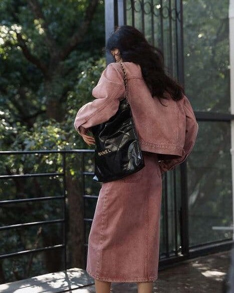 femme portant une longue jupe en jean rose de la collection ulma, vue de dos avec un sac à main noir à l'extérieur