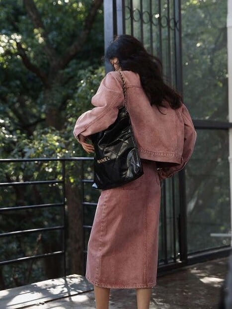 femme portant une longue jupe en jean rose de la collection ulma, vue de dos avec un sac à main noir à l'extérieur