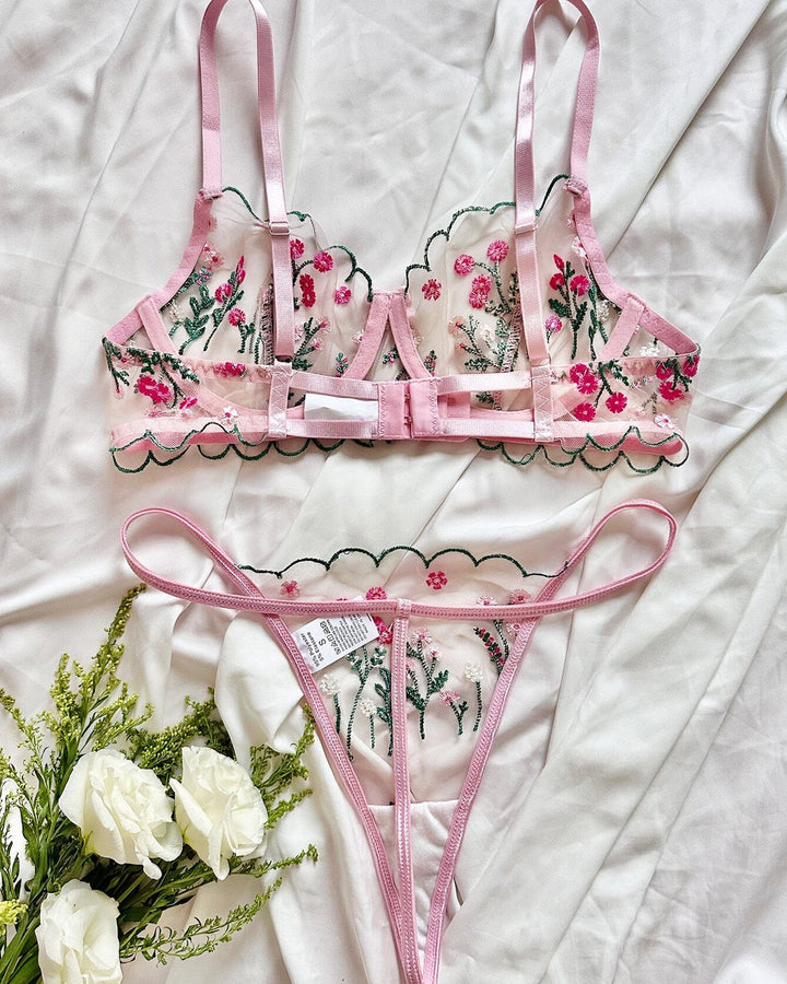 ensemble lingerie sexy fleuri jessica en dentelle rose avec motifs floraux sur fond blanc et fleurs blanches en décoration