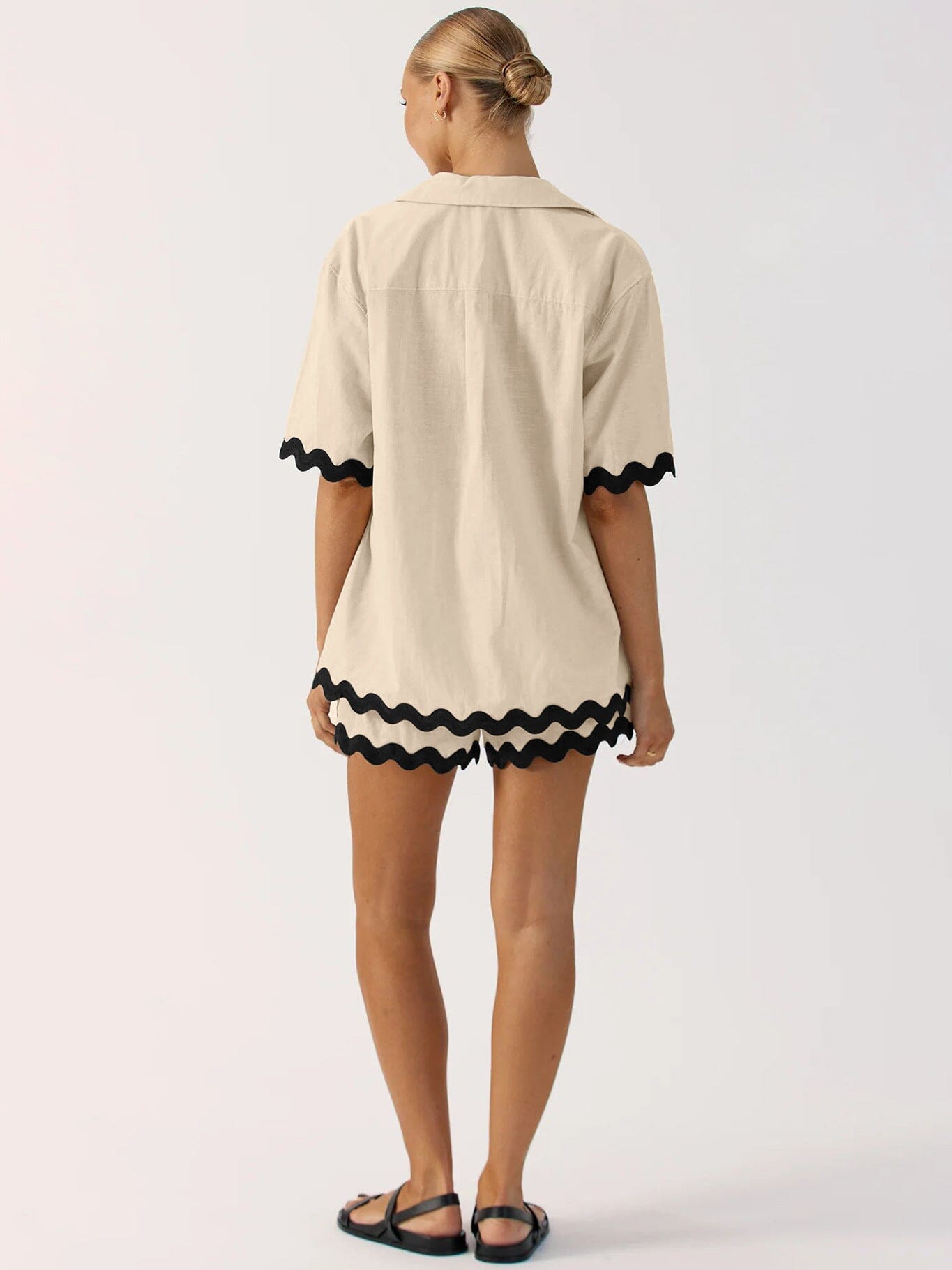 Vue arrière d'une femme portant un ensemble chemise et short beige avec des motifs ondulés noirs