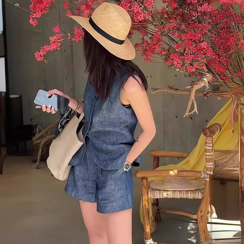 femme portant un ensemble short et tee-shirt en jean avec un chapeau de paille, devant une décoration florale intérieure