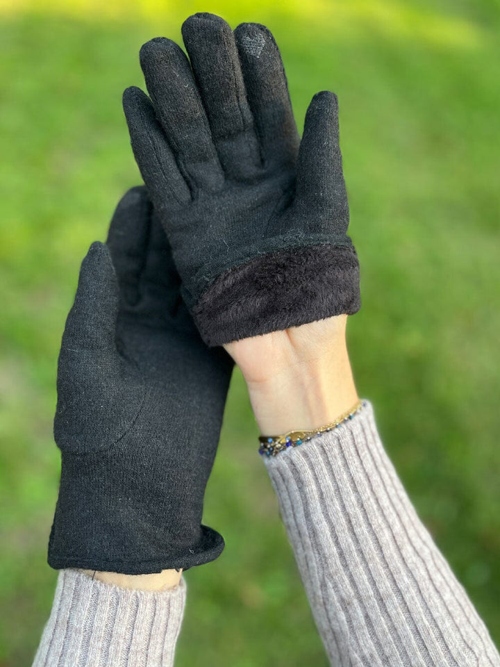 gants tactiles polaire noir pour femme léna posés sur une table avec une tasse de café et un bouton de jean