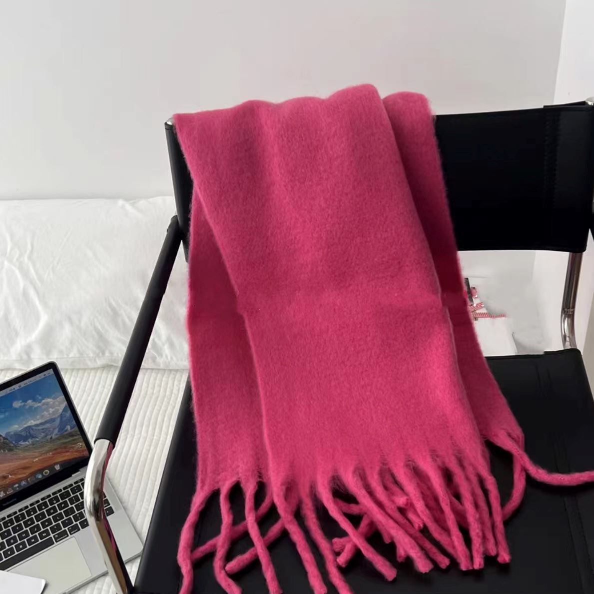 écharpe chaude pour femme couleur rose posée sur une chaise noire, idéale pour l'hiver et les températures fraîches