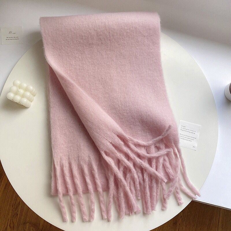 Écharpe chaude pour femme en laine rose avec des franges, modèle Cindy, posée sur une table blanche, accessoire élégant pour l'hiver