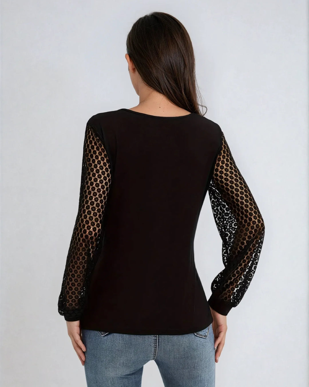 Vue arrière d'un haut noir à manches longues en dentelle porté avec un jean, mettant en valeur le style élégant.