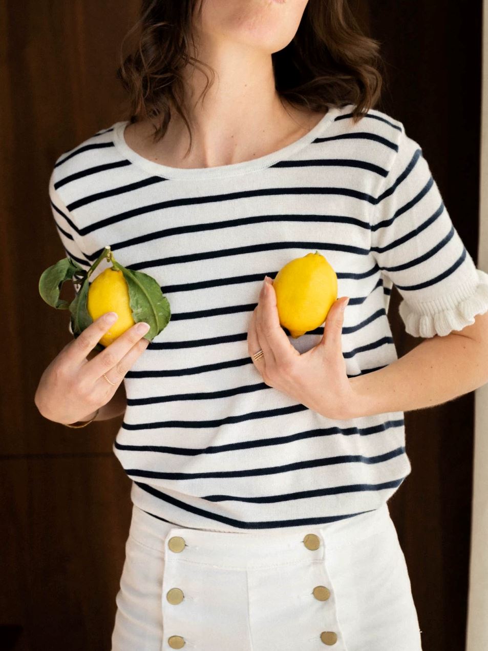 femme portant un haut marinière rayé blanc et noir édition limitée, t-shirt marinière, tenant des citrons jaunes.