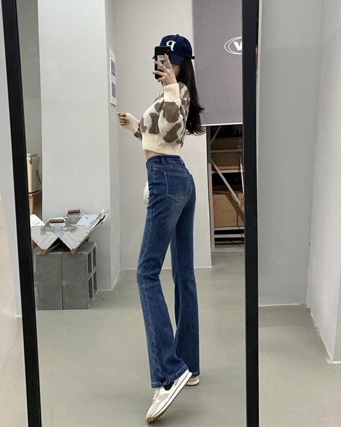 Jean flare taille haute Paige porté par mannequin devant un miroir, mettant en valeur sa silhouette élégante et moderne.