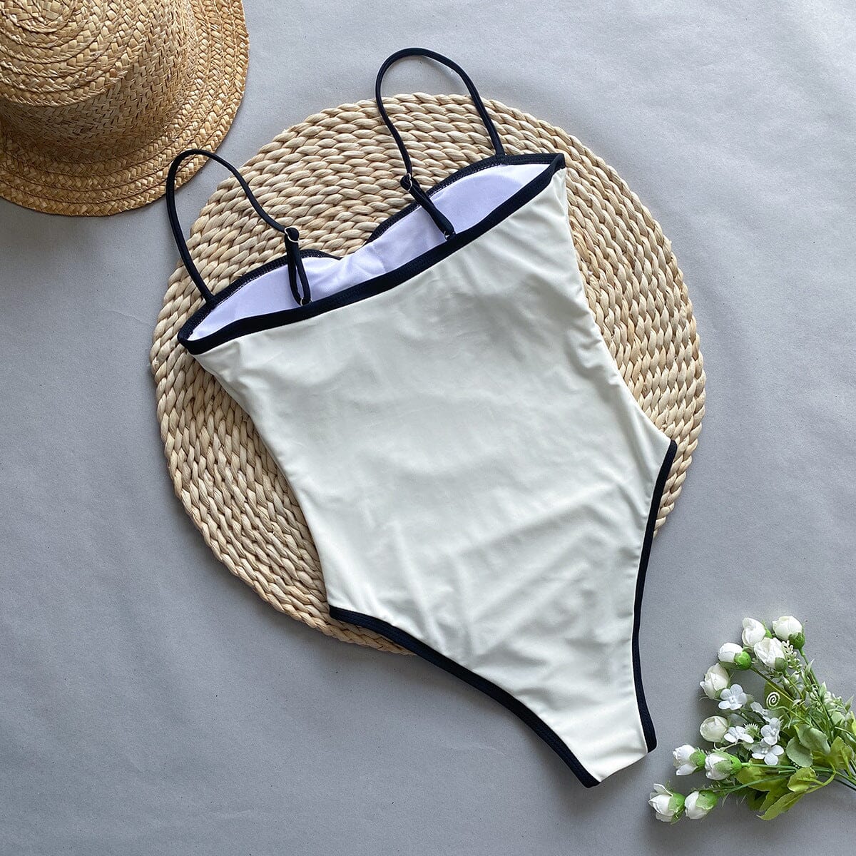 maillot de bain une pièce gainant échancré blanc - garance, présenté sur un tapis de jute avec un chapeau et des fleurs sauvegarde