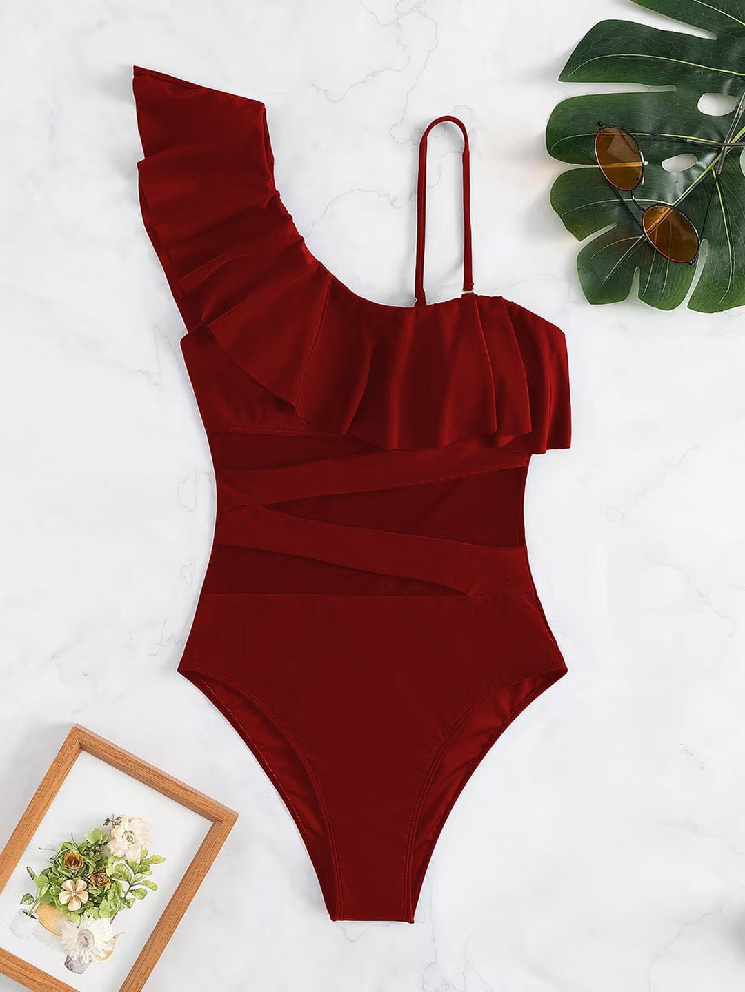 maillot de bain 1 pièce gainant asymétrique rouge malika avec volants et bretelles, accessoires estivaux en arrière-plan