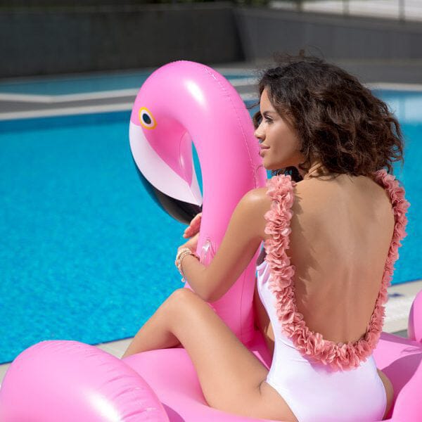 maillot de bain une pièce iris avec fleurs au bord de la piscine, femme assise sur une bouée flamant rose