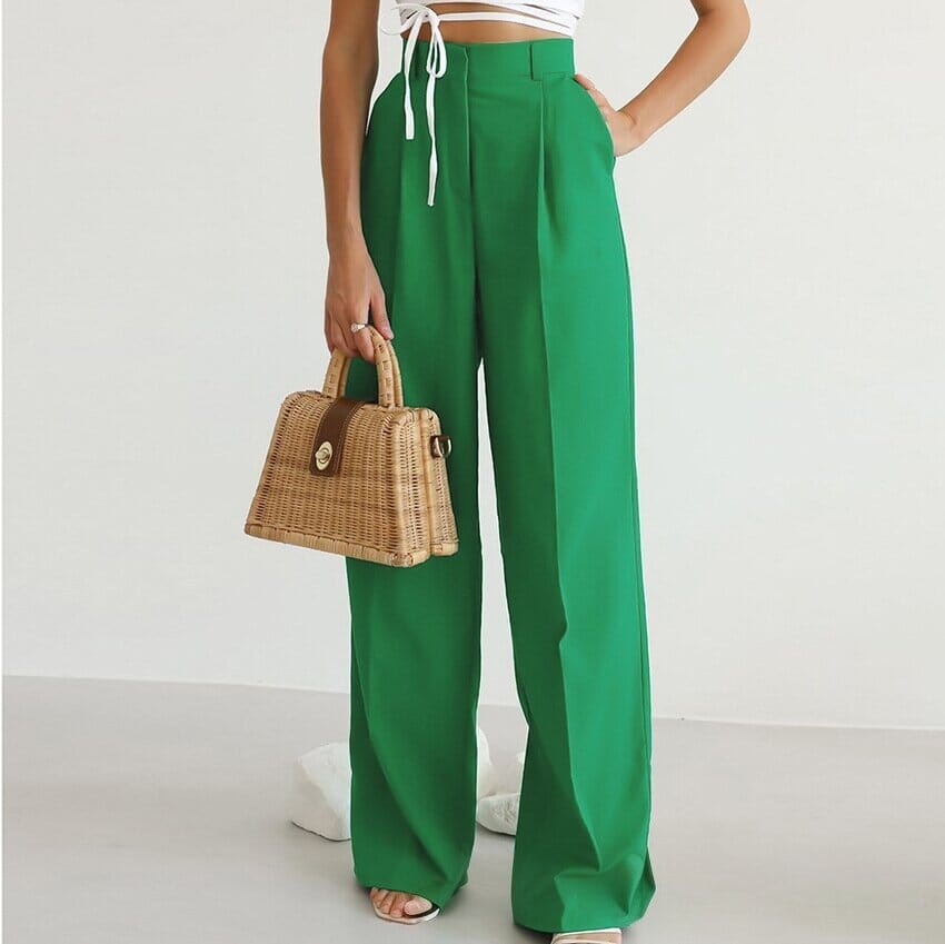 pantalon vert fluide taille haute en tissu léger porté par une femme avec un haut blanc à lacets et un sac en osier