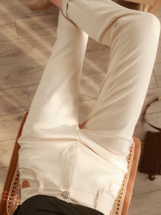pantalon léger pour femme, parfait pour l'été, de couleur claire, photographié en vue plongeante sur une chaise.