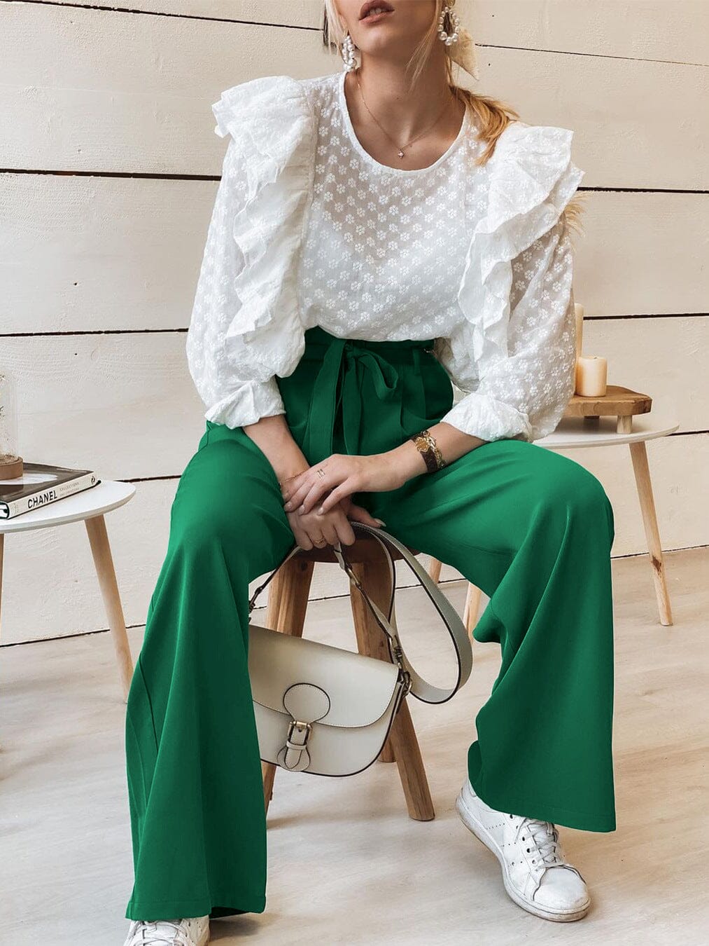 femme assise portant un pantalon fluide vert taille haute olga et chemisier blanc volanté, avec sac blanc