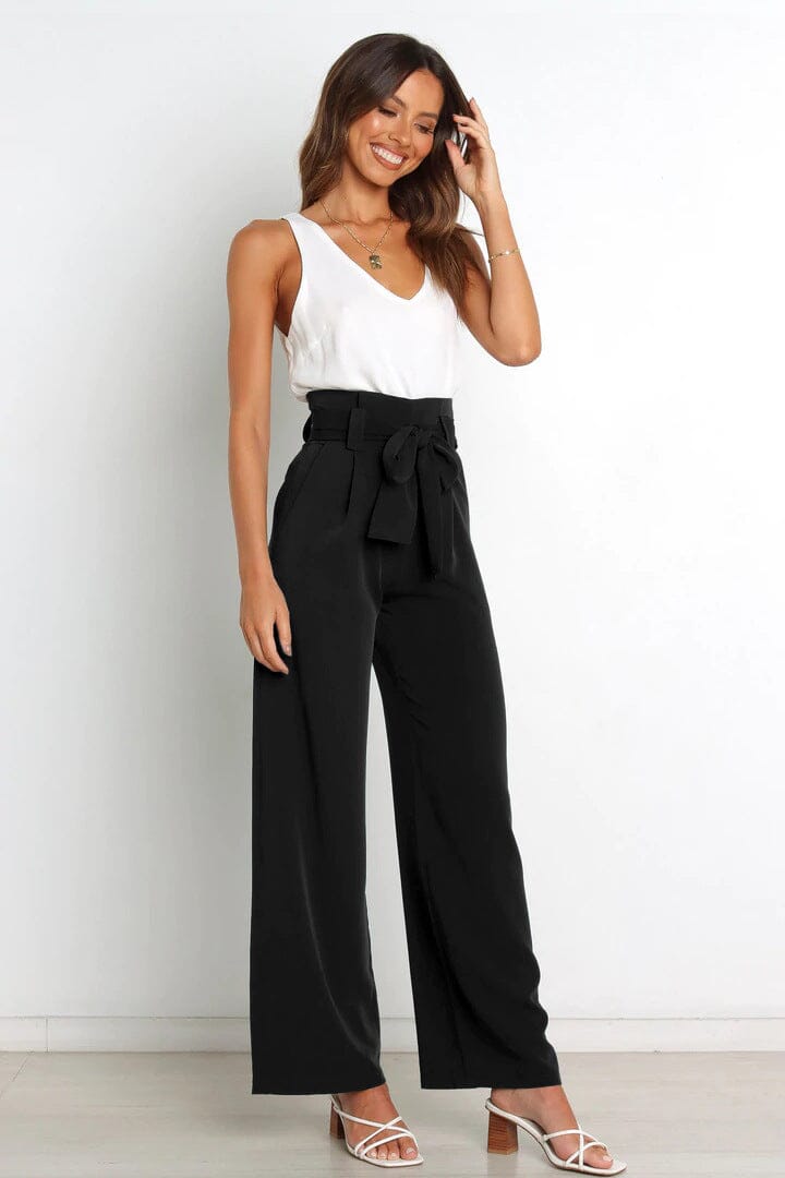 femme portant un pantalon fluide taille haute noir avec une ceinture et un haut blanc sans manches