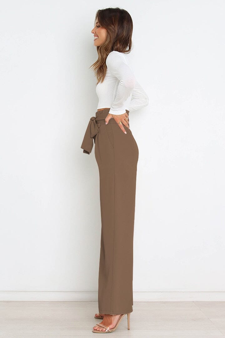 pantalon fluide taille haute olga en beige porté par un modèle de profil, associé à un haut blanc ajusté et à des talons hauts.