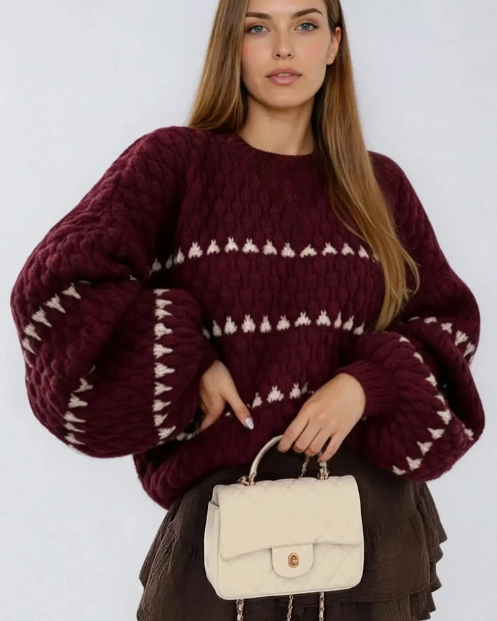 Une femme porte un pull en maille point boule couleur bordeaux, design moderne et élégant idéal pour l'automne.