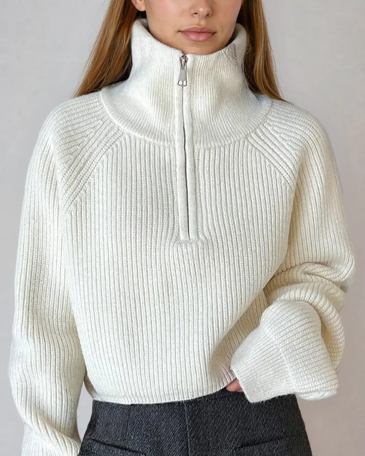 Femme portant un élégant pull à zip court en laine douce, de couleur blanche, avec col haut idéal pour l'hiver.
