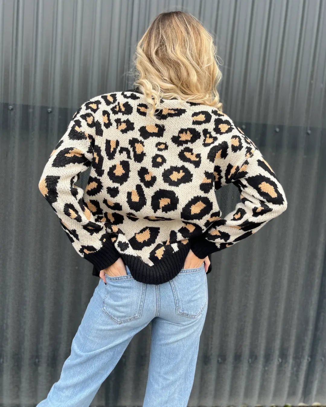 Pull léopard Josie porté par une femme, vue de dos avec un fond industriel, style décontracté et élégant.