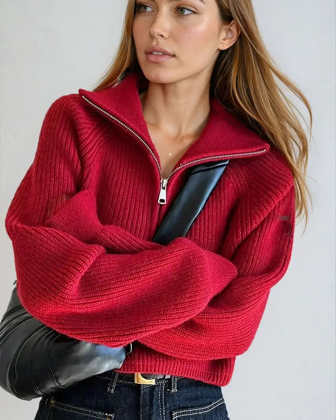 Femme portant un pull rouge à zip court avec un sac noir, style moderne et décontracté, idéal pour l'automne.