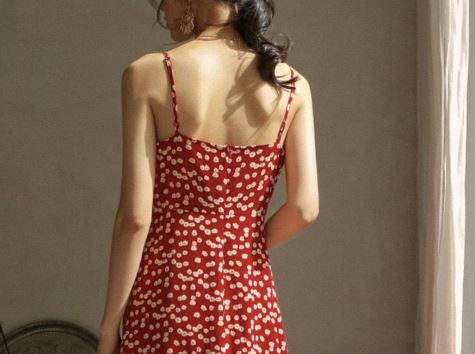 femme portant une robe longue rouge à fleurs blanches, vue de dos, parfaite pour une tenue élégante et estivale