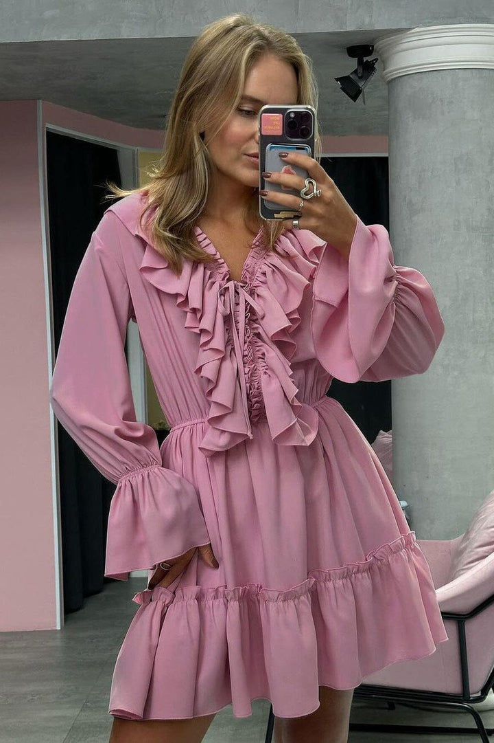 jeune femme portant une robe rose à volants avec manches longues et photographiée devant un miroir